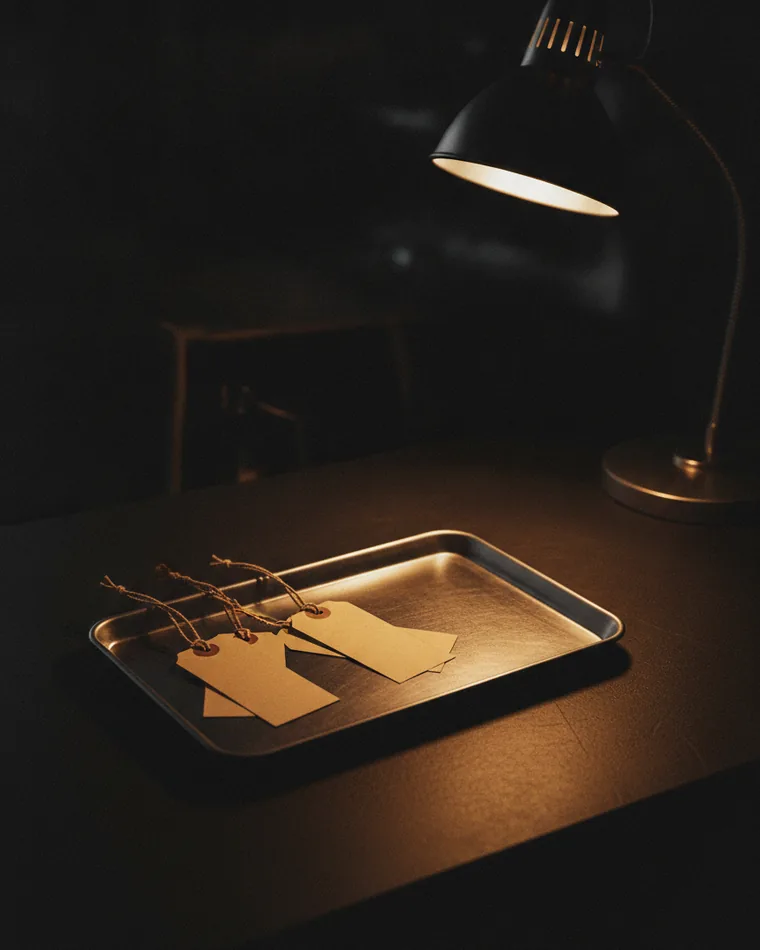 A shallow tray of small blank luggage tags on a dark desk, most of the tray empty.