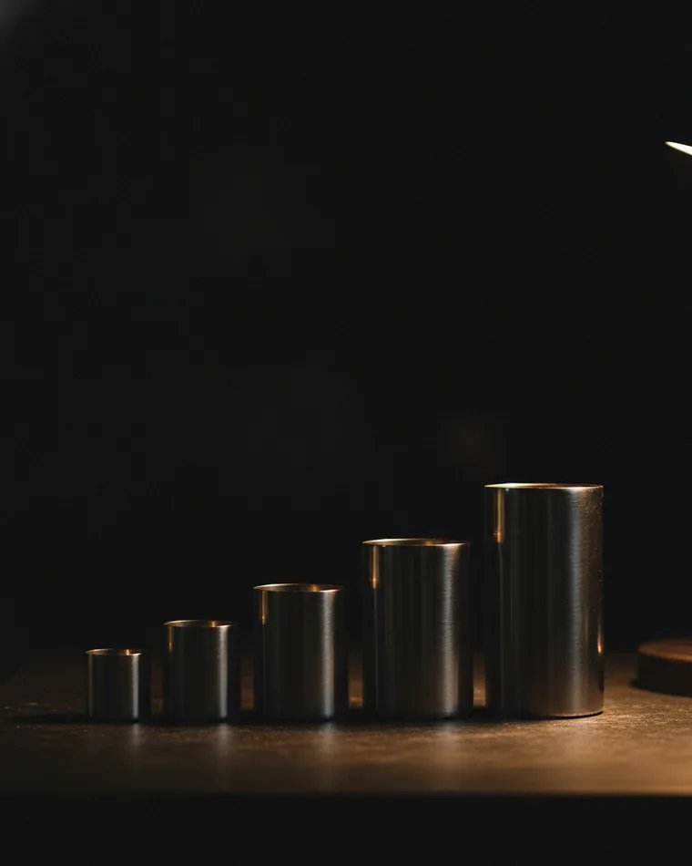 A set of nested measuring cylinders standing on a dark bench in ascending order.