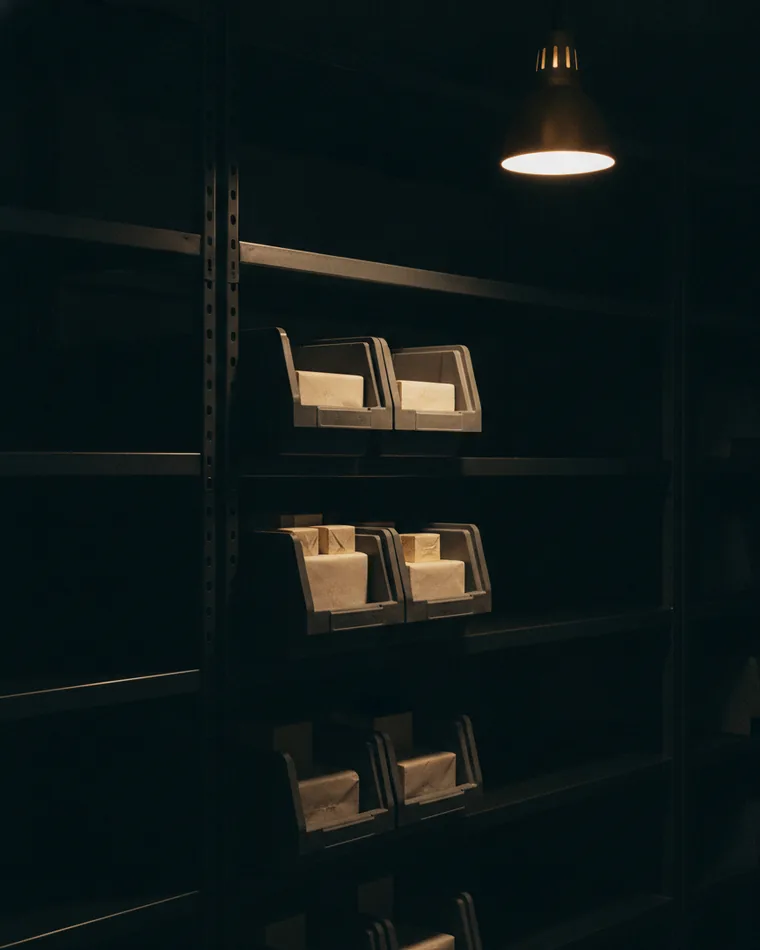 Stacked parts bins on a dark shelf, two pulled forward and holding plain wrapped items.